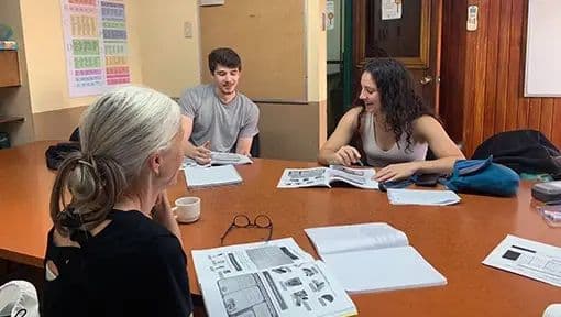 Three students and a teacher working with newspapers on a wooden table