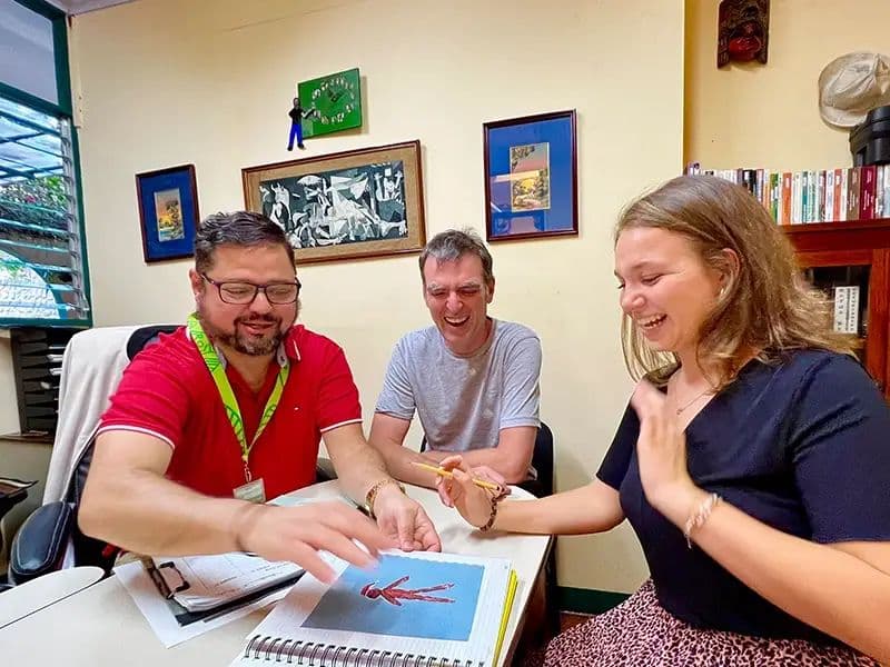 A small group lesson around a table, the teacher pointing at a vocabulary sheet